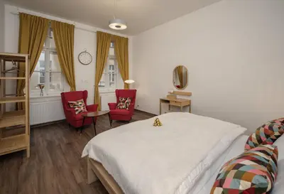 a bedroom with a bed and two red chairs at Unesco Prague Apartments in Prague