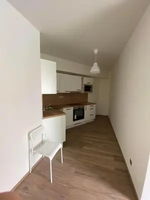 a white kitchen with a chair and a table at Apartment David O2 Arena Prague in Prague