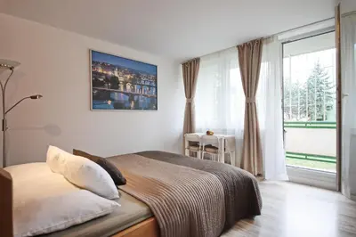 a bedroom with a bed and a large window at Invalidovna Apartment in Prague