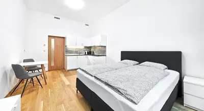 a bedroom with a bed and a table and a kitchen at Apartments Harfa in Prague