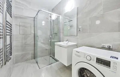 a bathroom with a washing machine and a shower at Apartments Harfa in Prague