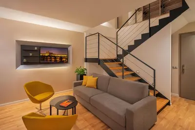 a living room with a couch and a staircase at Hotel CUBE Prague in Prague