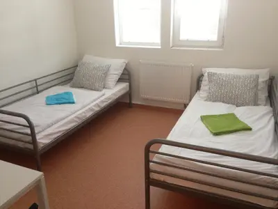 two beds in a small room with two windows at Hostel BOHEMIA in Prague