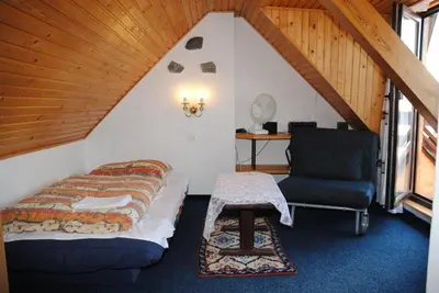 a bedroom with a bed and a chair in a attic at Chalet Lucie in Mnetěš