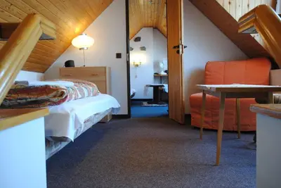 a bedroom with a bed and a chair in a room at Chalet Lucie in Mnetěš