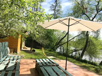 a picnic table with an umbrella and benches at Sazava River Cottage with boating experience in Týnec nad Sázavou