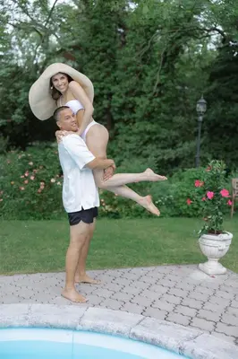 a man holding a woman on his back by a pool at Penzion Na Staré Poště in Nymburk