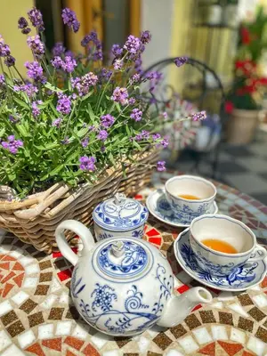 a table with three cups of tea and a basket of flowers at Penzion Na Staré Poště in Nymburk