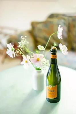 a bottle of wine sitting next to a vase of flowers at Penzion Na Staré Poště in Nymburk