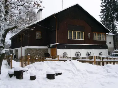 a house covered in snow with a fence at Lovecký hotel Jívák in Loučeň