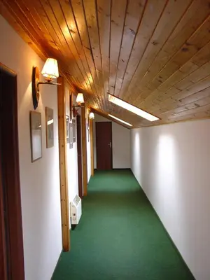 a hallway with a green floor and a wooden ceiling at Lovecký hotel Jívák in Loučeň