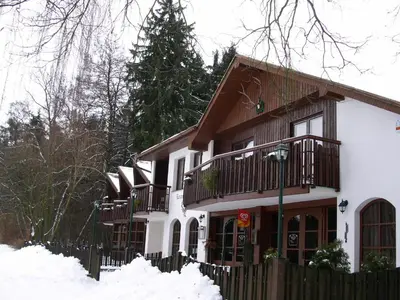 a white house with a wooden fence in the snow at Lovecký hotel Jívák in Loučeň