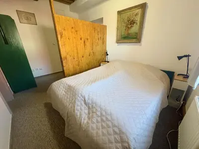 a bedroom with a bed with a green headboard and two night stands at Bendovský dvůr in Dušníky
