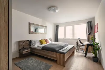 a bedroom with a bed and a desk and a window at Prague Days - Apartment with Balcony and Parking in Trendy New Residential Area in Karlín in Prague