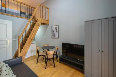 a living room with a table and a staircase at Main train station apartment close to the the Main Square! in Prague