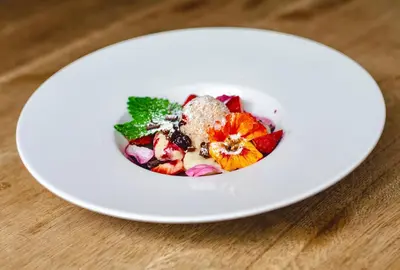 a white plate with a fruit salad on a table at Resort Čapí Hnízdo in Olbramovice Ves
