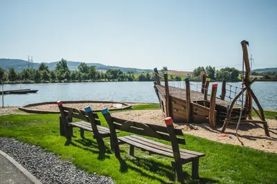 a park bench next to a boat on the water at Resort Čapí Hnízdo in Olbramovice Ves