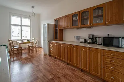 a kitchen with wooden cabinets and a table and a refrigerator at Super Central Billiard and Darts Big Apartment in Prague