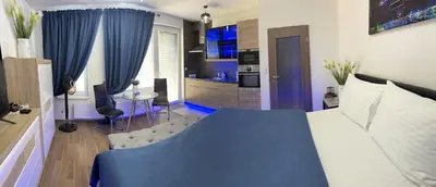 a bedroom with a blue bed and a living room at Apartment IRON CUBE in Prague