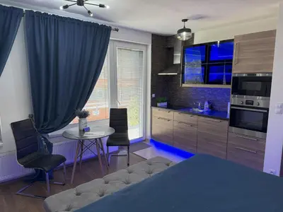a room with a bed and a table and a kitchen at Apartment IRON CUBE in Prague