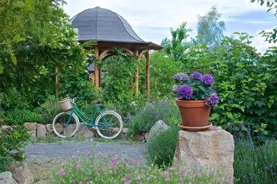 a bike parked in a garden with a gazebo at Babiččina Zahrada Penzion & Restaurant in Pruhonice