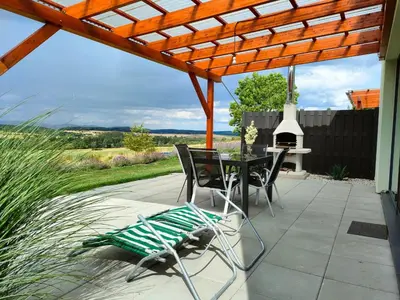 a patio with a table and chairs under a pergola at Panorama house Brdy in Příbram