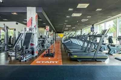 a gym with a row of treadmills and machines at Blue Orange Resort in Prague