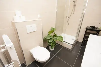 a bathroom with a toilet and a shower and a plant at Fashion Loft in Prague