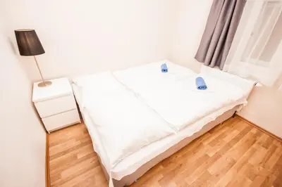 two beds in a white room with wooden floors at Fashion Loft in Prague