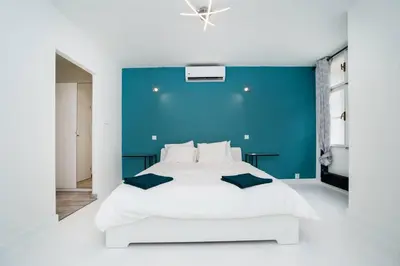 a bedroom with a large white bed with a blue wall at Old Town 1 Bedroom Oasis with AC and Double Shower in Prague