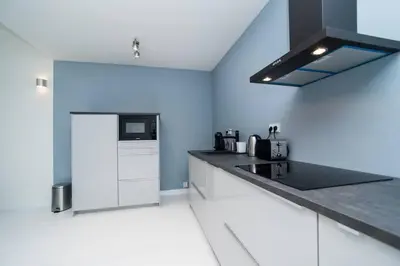 a kitchen with white cabinets and a black counter top at Old Town 1 Bedroom Oasis with AC and Double Shower in Prague