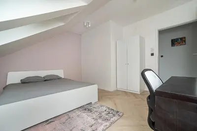 a white bedroom with a bed and a desk at Big 4-bedroom flat, terrace with great Vítkov view in Prague