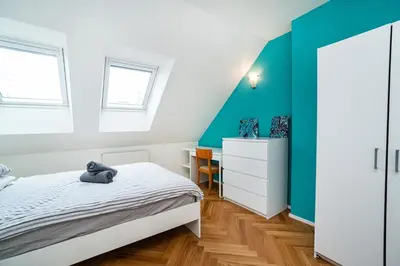 a bedroom with a bed and a blue accent wall at Central, Spacious, Modern 5 Bedrm duplex w/Balcony in Prague