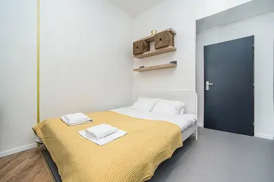 a bedroom with a bed with a yellow blanket and a blue door at Central designer studio by beautiful park & church in Prague