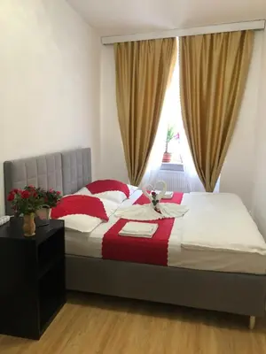 a bed with red and white pillows and a window at Lena Apartment in Prague