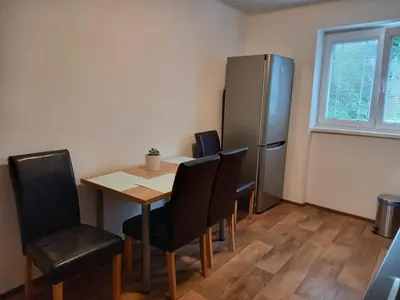 a dining room table with chairs and a refrigerator at Apartmán Matěj in Poděbrady