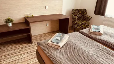 a hotel room with two beds and a chair at Penzion Ranch in Hořovice