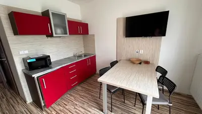 a small kitchen with a table and a sink and red cabinets at Penzion Ranch in Hořovice
