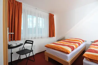 a bedroom with a bed and a chair and a window at Habitat 16 in Prague