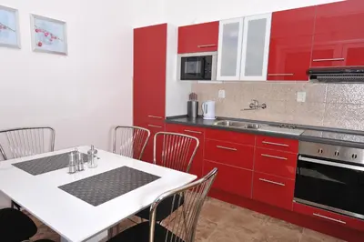 a kitchen with red cabinets and a white table with chairs at Habitat 16 in Prague