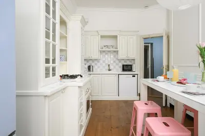a kitchen with white cabinets and pink stools at Airstay Prague : DeLuxe Apartment Old town in Prague