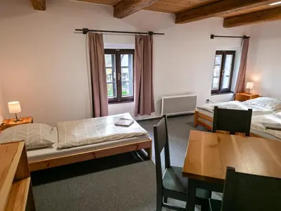 a room with two beds and a table and chairs at Pivovar Mlýn in Štětí