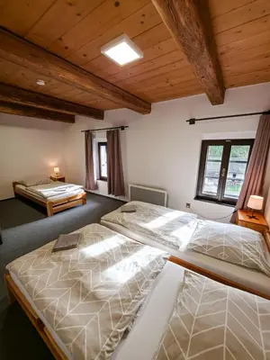 two beds in a room with wooden ceilings at Pivovar Mlýn in Štětí