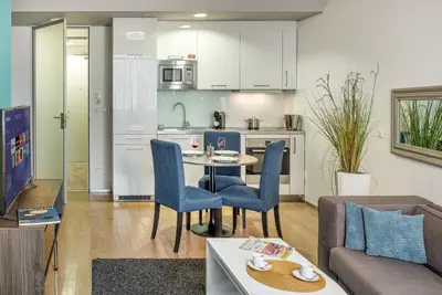 a living room with a table and chairs and a kitchen at VN3 Terraces Suites by Adrez in Prague