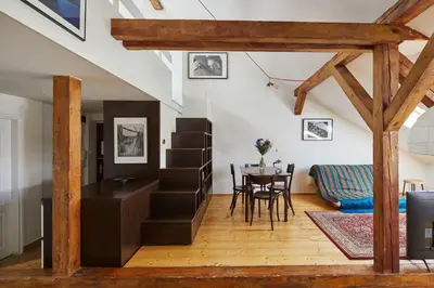 a living room with a staircase and a table at Prague Days - Open-plan Duplex with Corner Bath and Netflix in Vinohrady in Prague