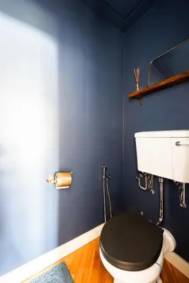 a blue bathroom with a toilet with a black lid at Victoria Design Stays - Premium Apartment Ohrada in Prague