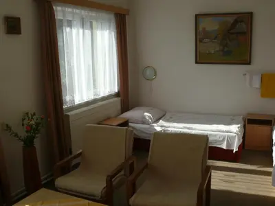 a room with two chairs and a bed and a window at Penzion Dana Troja in Prague