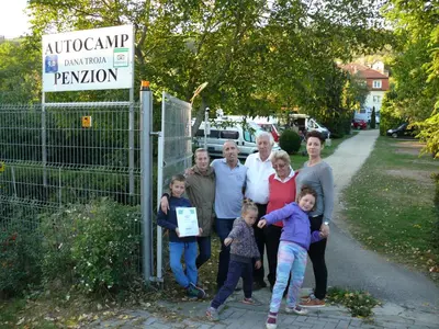 a family posing for a picture in front of a sign at Penzion Dana Troja in Prague