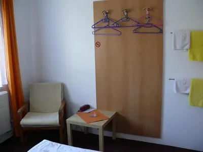 a room with a bed and a chair and a table at Penzion Dana Troja in Prague