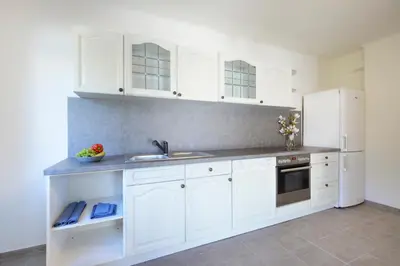 a kitchen with white cabinets and a sink and a refrigerator at Apartmány Jevany in Jevany